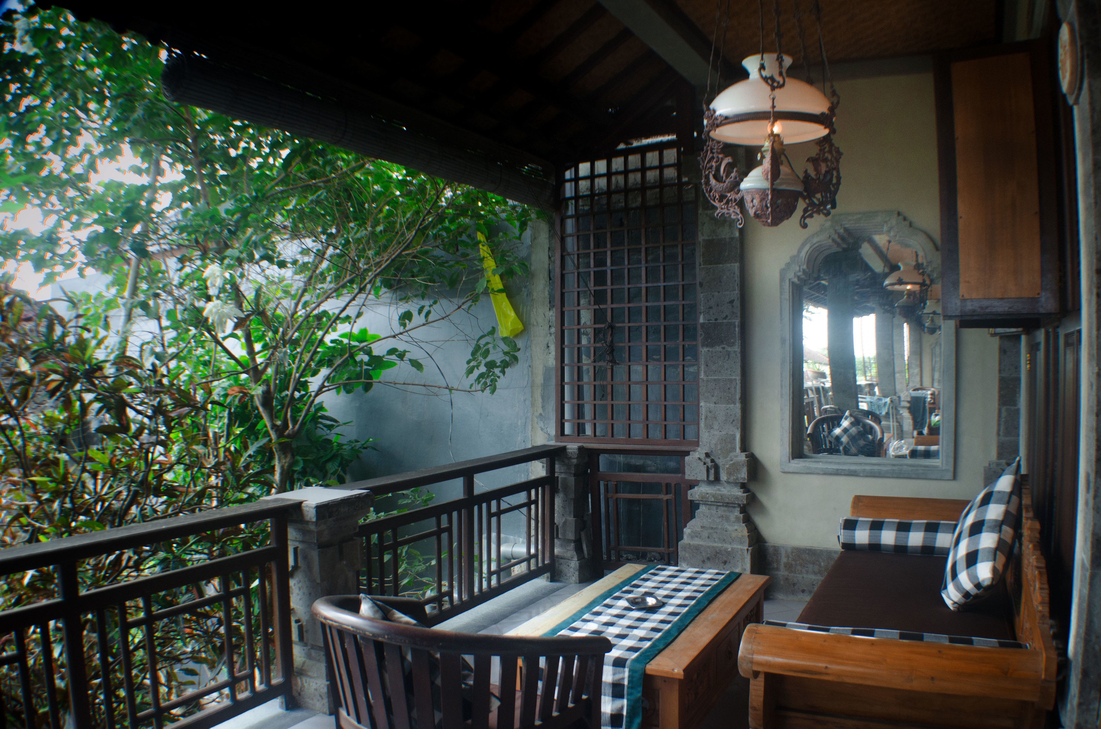 A traditional wooden bench with a checkered tablecloth, a hanging light fixture, and a view of lush greenery outside.