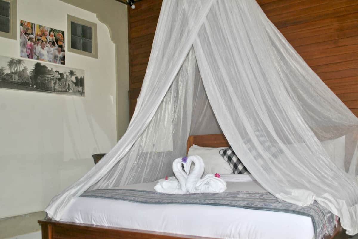 A bed with a canopy, white linens, and two swan-shaped towels.