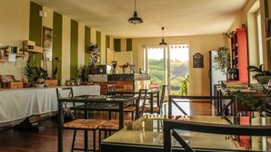 A dining area with tables and chairs, a view of the outdoors, and various plants and decorations. - Ca dei Currà (Neive)