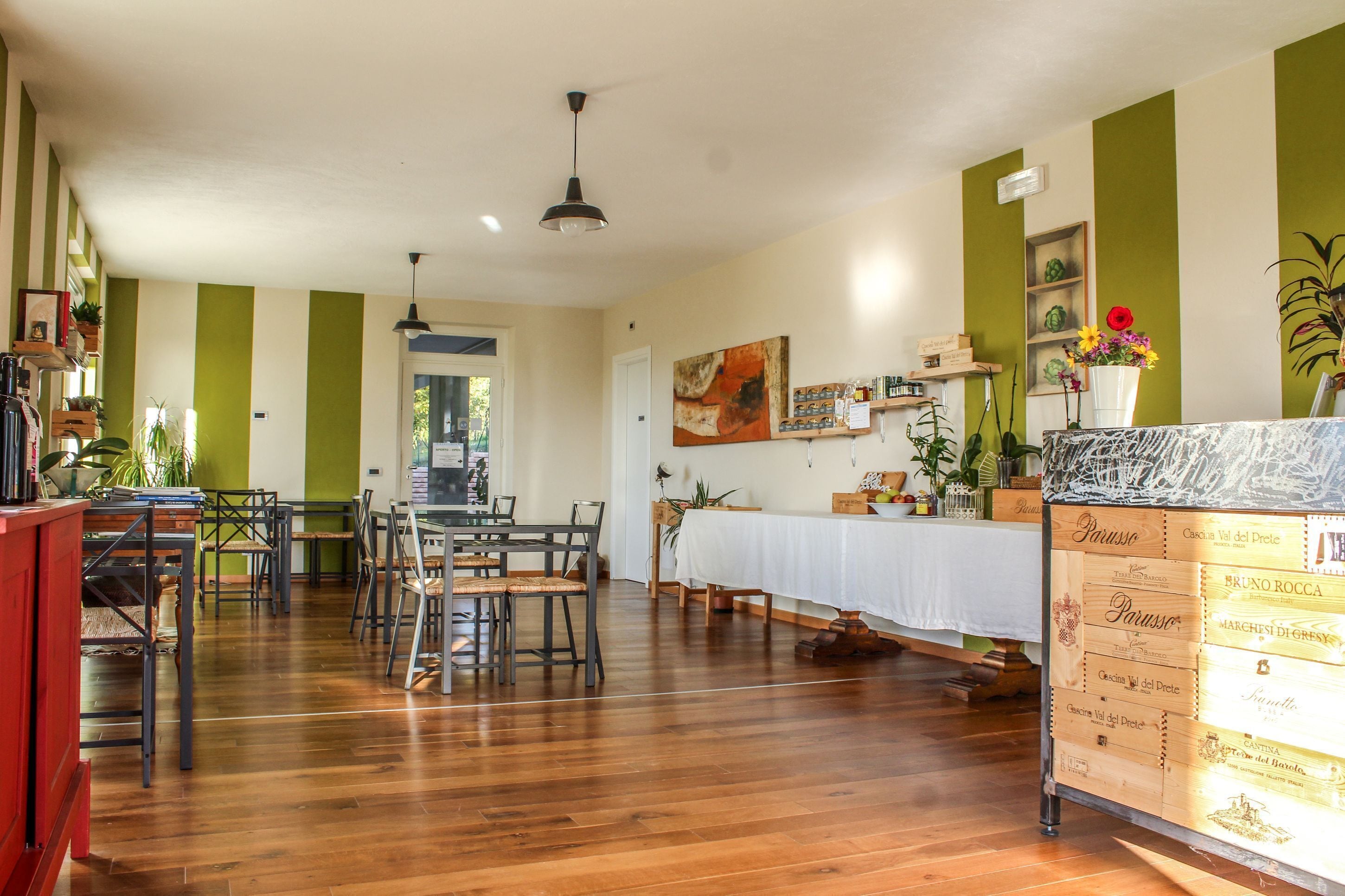 Un comedor con una mesa larga, sillas y un mueble de madera con etiquetas de vino.