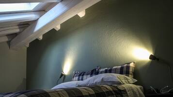 A room with a bed, a skylight, and a wall-mounted lamp.