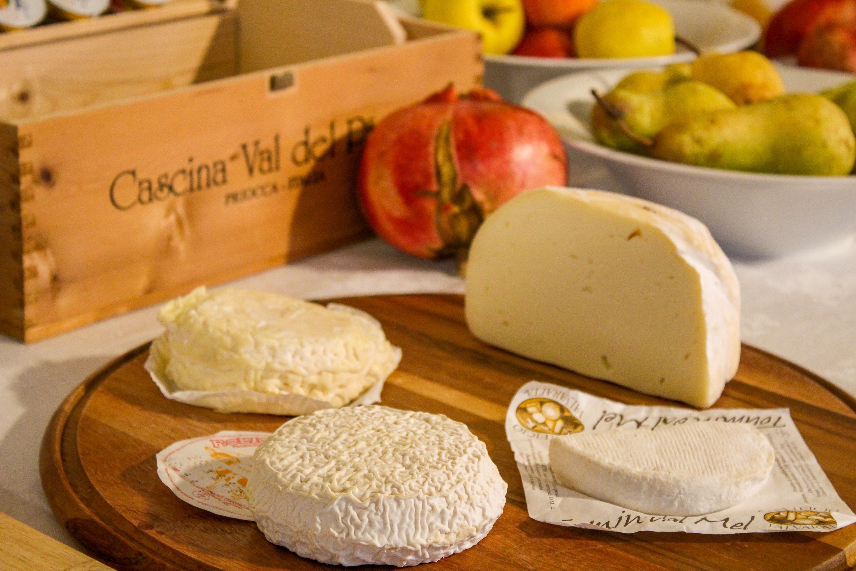 A wooden table with various cheeses and a box labeled "Cascina Val del Pera".