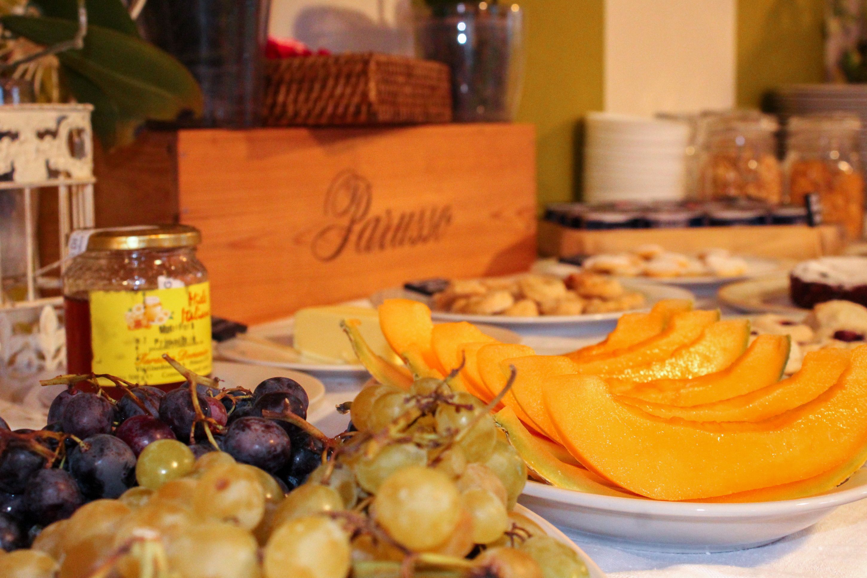 A table with various fruits and pastries, including grapes and sliced melons.