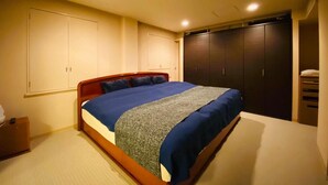 A bedroom with a large bed, a wardrobe, and a nightstand. - Hotel Free Style (Kofu)
