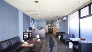 A hotel room with a seating area, a kitchenette, and a view of the outside. - Hotel Free Style (Kofu)