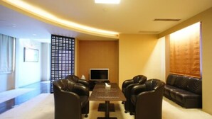 A modern room with a sofa set, a flat-screen TV, and a decorative partition. - Hotel Free Style (Kofu)