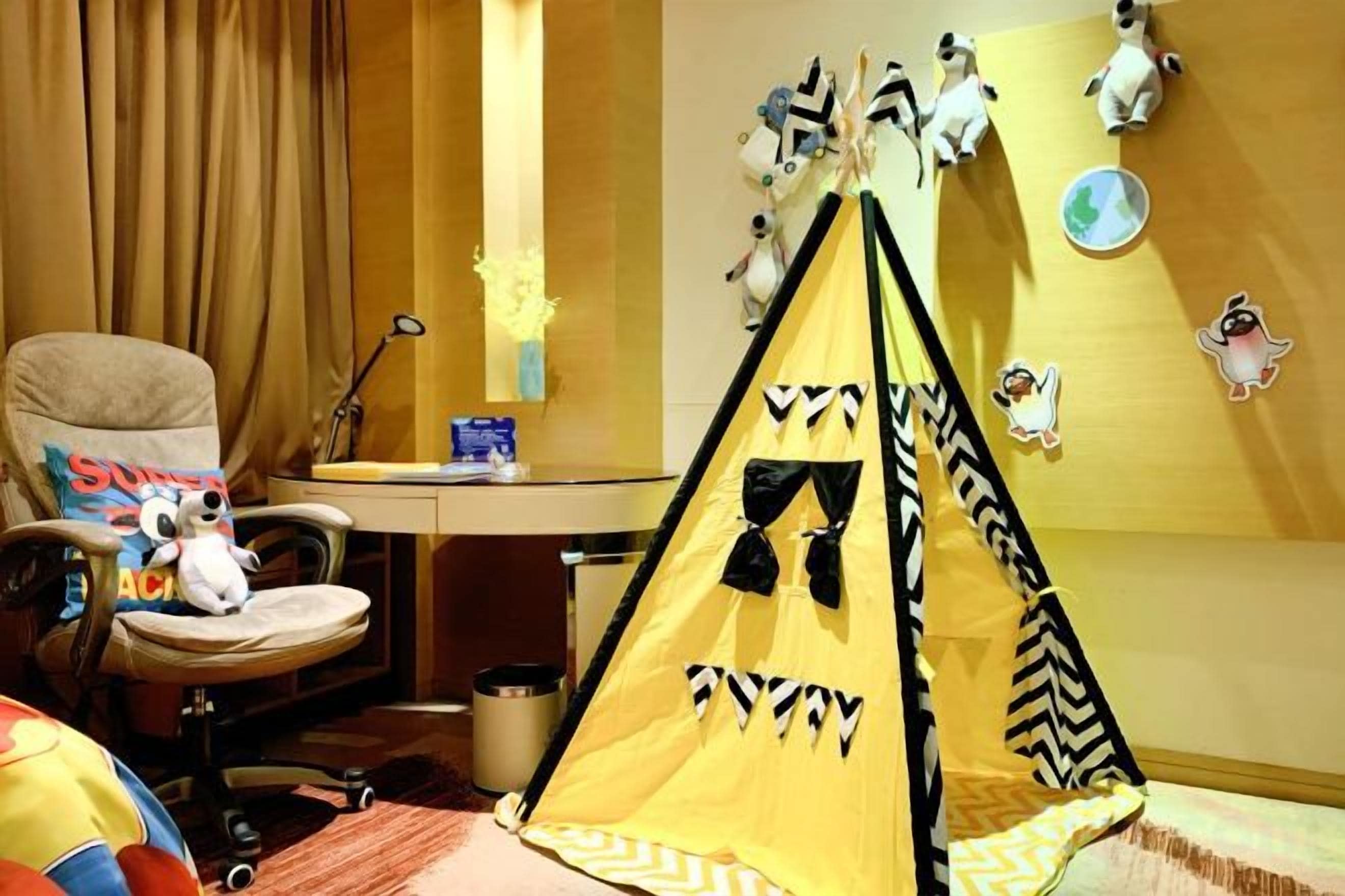 A room with a desk, chair, and a small tent-like structure.