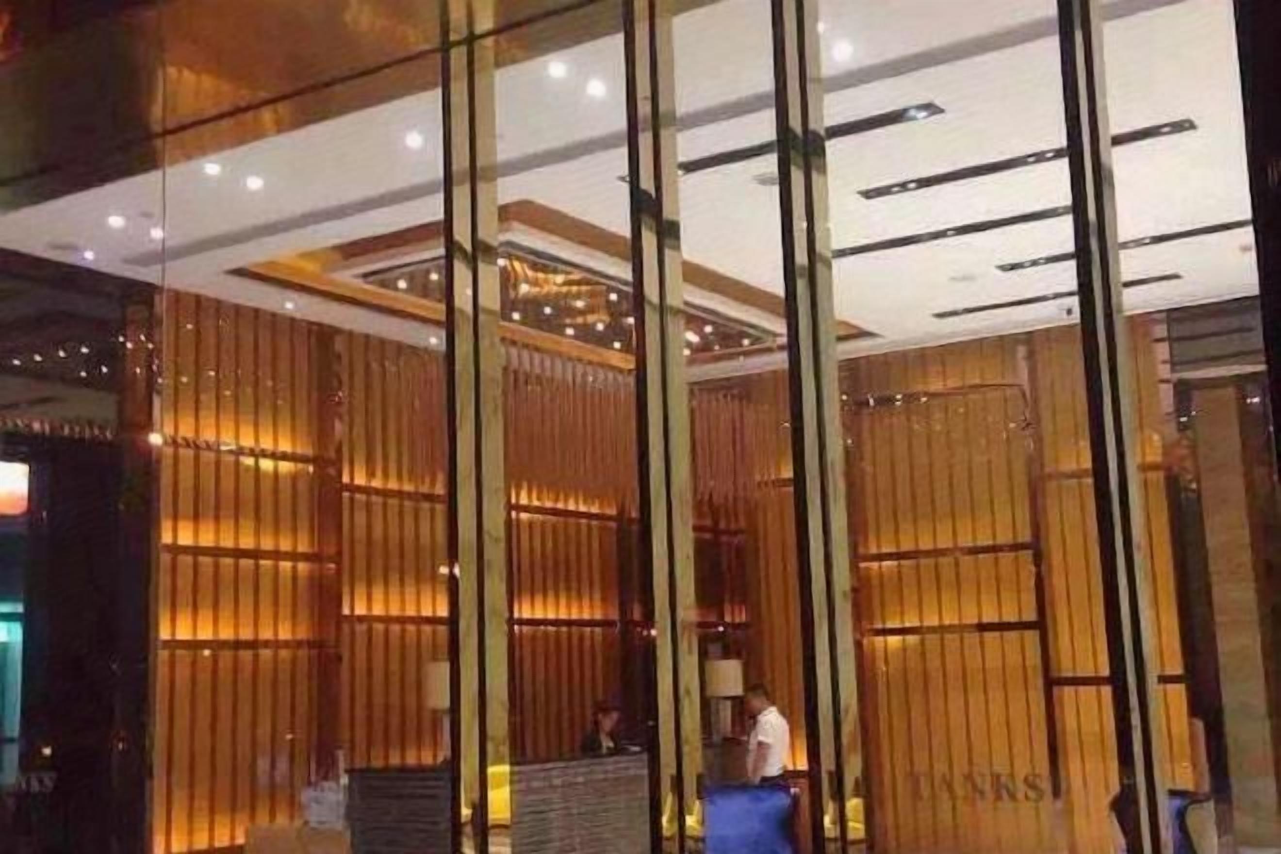 A reception area with a modern design, featuring a reception desk, a seating area, and a large glass partition.