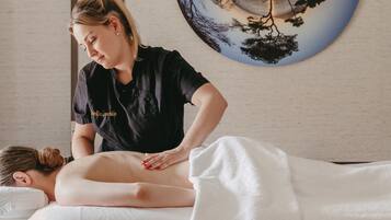 A massage therapy session in a room with a large circular artwork on the wall.