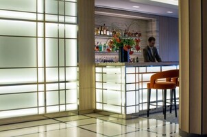 Zona bar moderna con una parete divisoria in vetro, un bancone e una zona con due sedie.