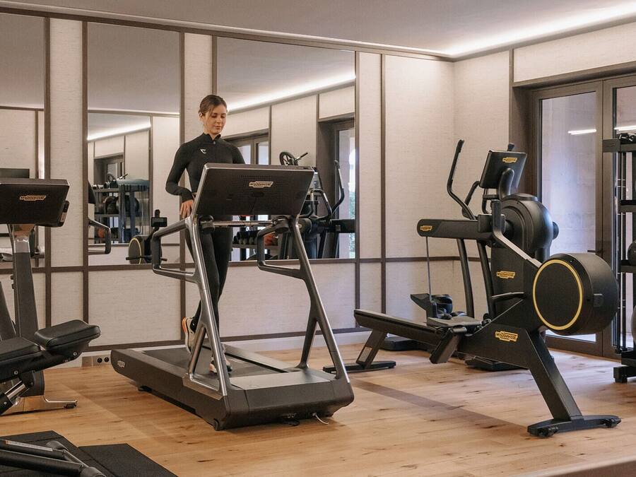 Un gimnasio con cintas de correr, máquinas de pesas y pelotas de ejercicio.