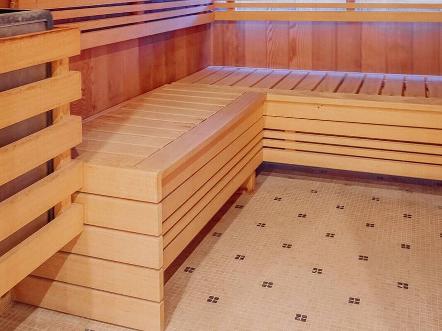 A wooden sauna with benches and a tiled floor.