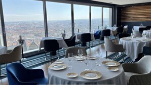 Un restaurante con mesas redondas, sillas y vistas a la ciudad.