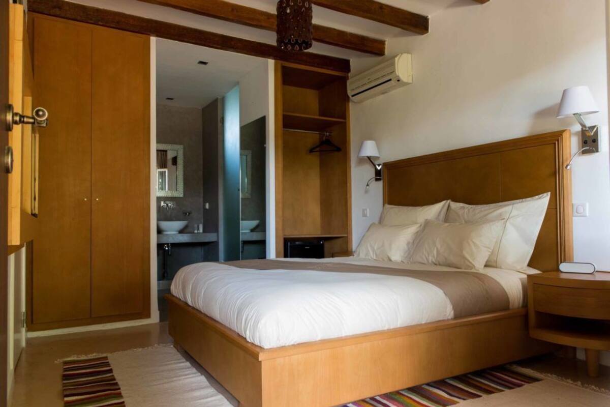 Une chambre à coucher avec un lit en bois, une table de chevet, une lampe et une armoire.