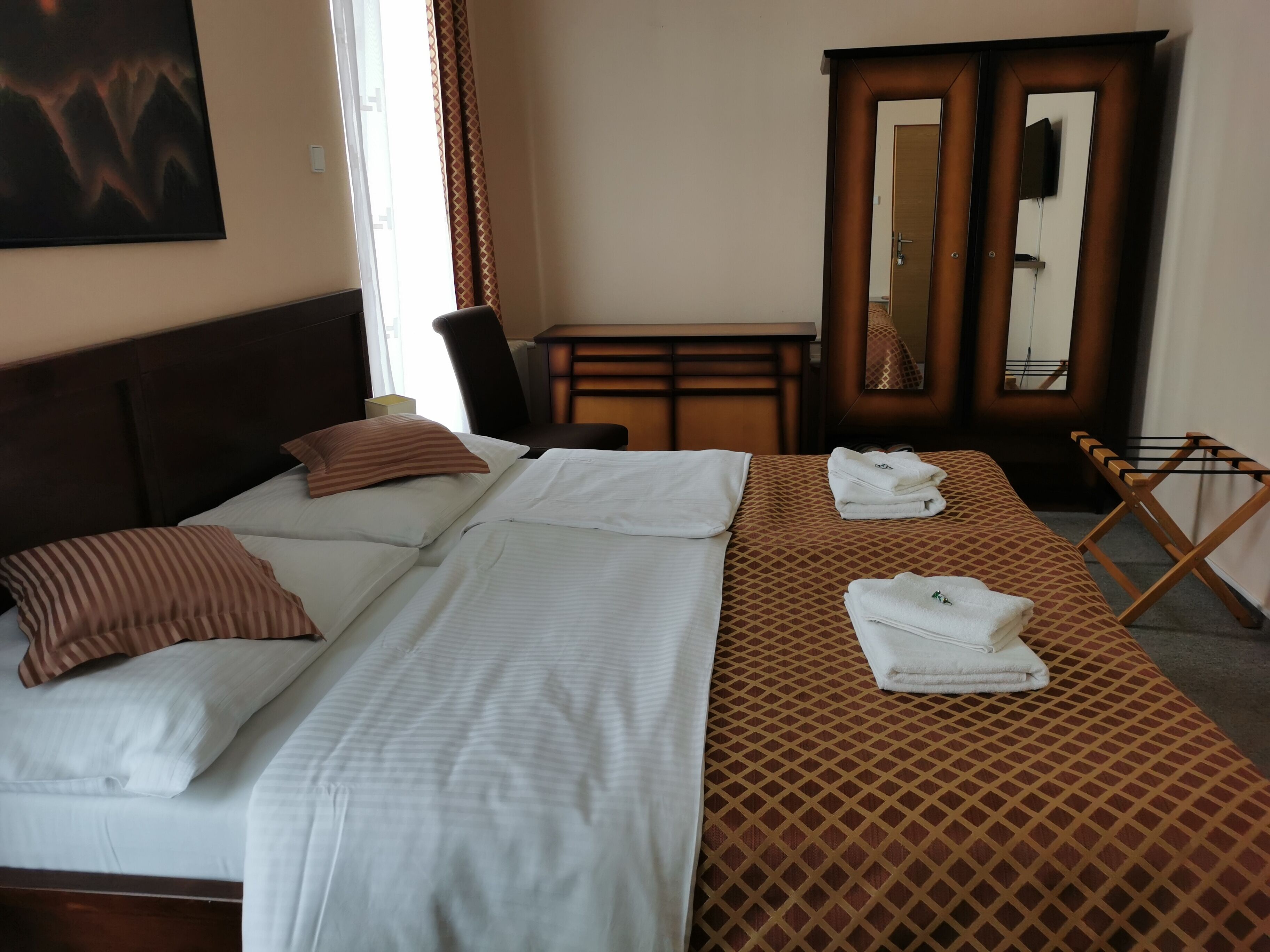 Une chambre d’hôtel avec un lit, un bureau, un miroir et une armoire.