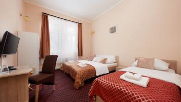 A hotel room with two beds, a desk, a chair, and a television.
