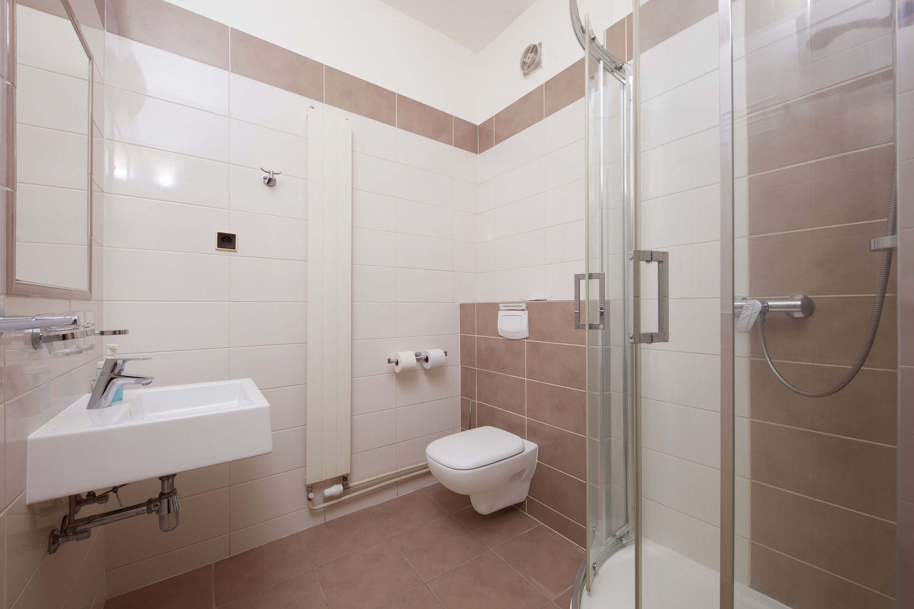 Un baño moderno con lavamanos, inodoro y ducha con mampara de vidrio.