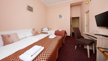 A hotel room with two beds, a desk, a chair, a television, and a door leading to another room.