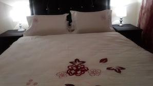 A bed with a dark headboard, two white pillows, and a floral-patterned bedspread. - The Royal Princess Garden - Honeydew (Roodepoort)