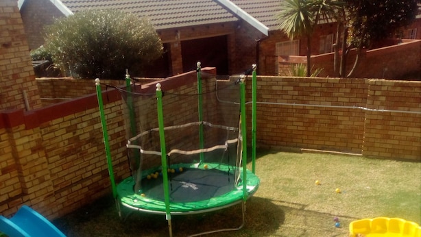 A fenced backyard with a trampoline, a blue slide, and a yellow sandbox. - The Royal Princess Garden - Honeydew (Roodepoort)