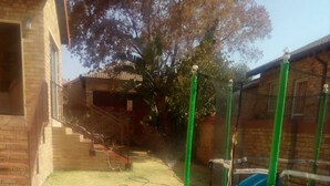 A backyard with a trampoline, a yellow playpen, and a slide. - The Royal Princess Garden - Honeydew (Roodepoort)