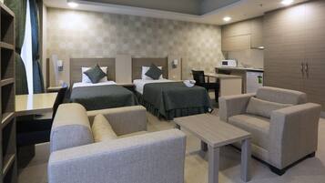 Habitación de hotel con dos camas, un escritorio, una silla, un sofá y una kitchenette.
