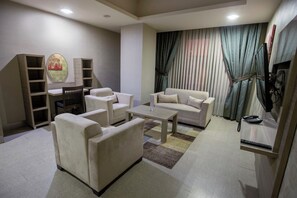 A modern living room with a sofa set, a coffee table, and a TV stand with a phone. - Sakarya Sen Hotel (Serdivan)
