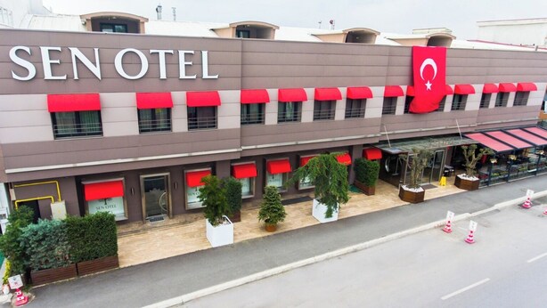 A hotel with a modern facade, red awnings, and a prominent flag. - Sakarya Sen Hotel (Serdivan)