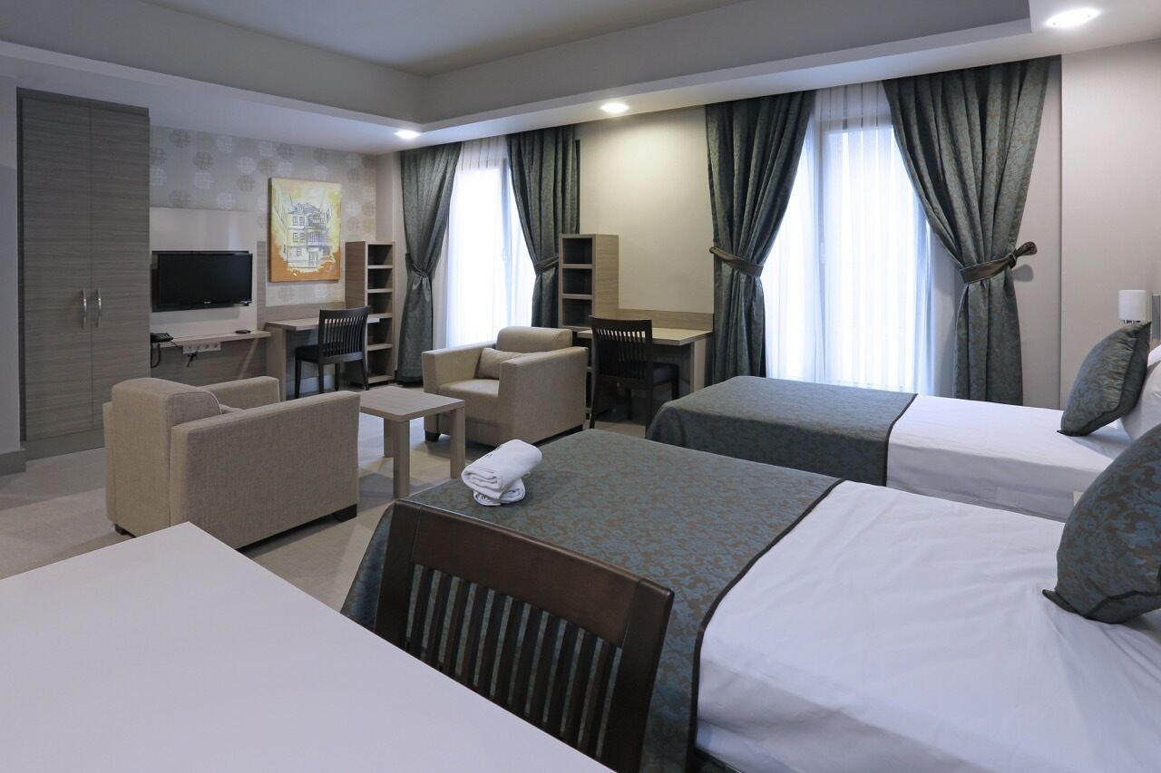 Una habitación de hotel con dos camas, un escritorio, una silla, un sofá y un televisor.
