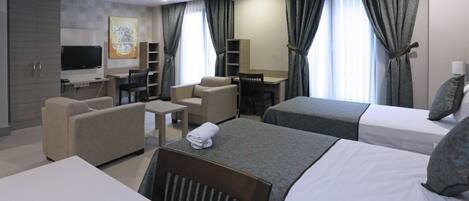 Una habitación de hotel con dos camas, un escritorio, una silla, un sofá y un televisor.