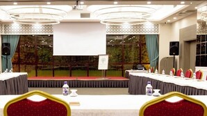 A conference room with a long table, red chairs, and a projector screen. - Sakarya Sen Hotel (Serdivan)