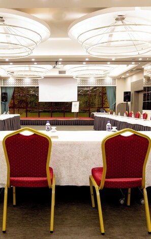 A conference room with a long table, red chairs, and a projector screen. - Sakarya Sen Hotel (Serdivan)