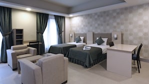 A hotel room with two beds, a desk, a chair, a sofa, and a bookshelf. - Sakarya Sen Hotel (Serdivan)