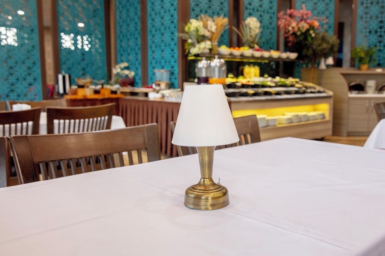 A table with a white tablecloth and a brass lamp in a restaurant setting.