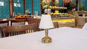 A table with a white tablecloth and a brass lamp in a restaurant setting.