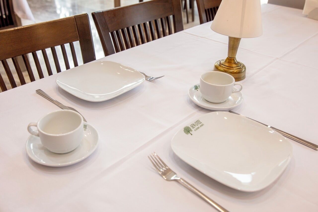 A table set with a plate, a cup, a saucer, a fork, and a spoon.