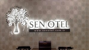 A hotel reception area with a sign reading 'SEN OTEL' and a website address. There is a table with two chairs in front of the sign. - Sakarya Sen Hotel (Serdivan)