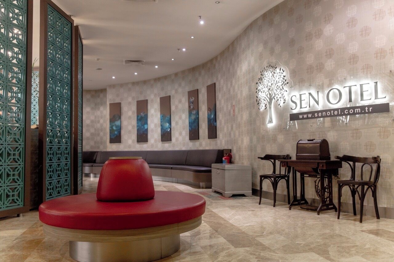 A hotel lobby with a reception desk, seating area, and a wall-mounted sign.