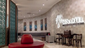 A hotel lobby with a reception desk, seating area, and a wall-mounted sign. - Sakarya Sen Hotel (Serdivan)