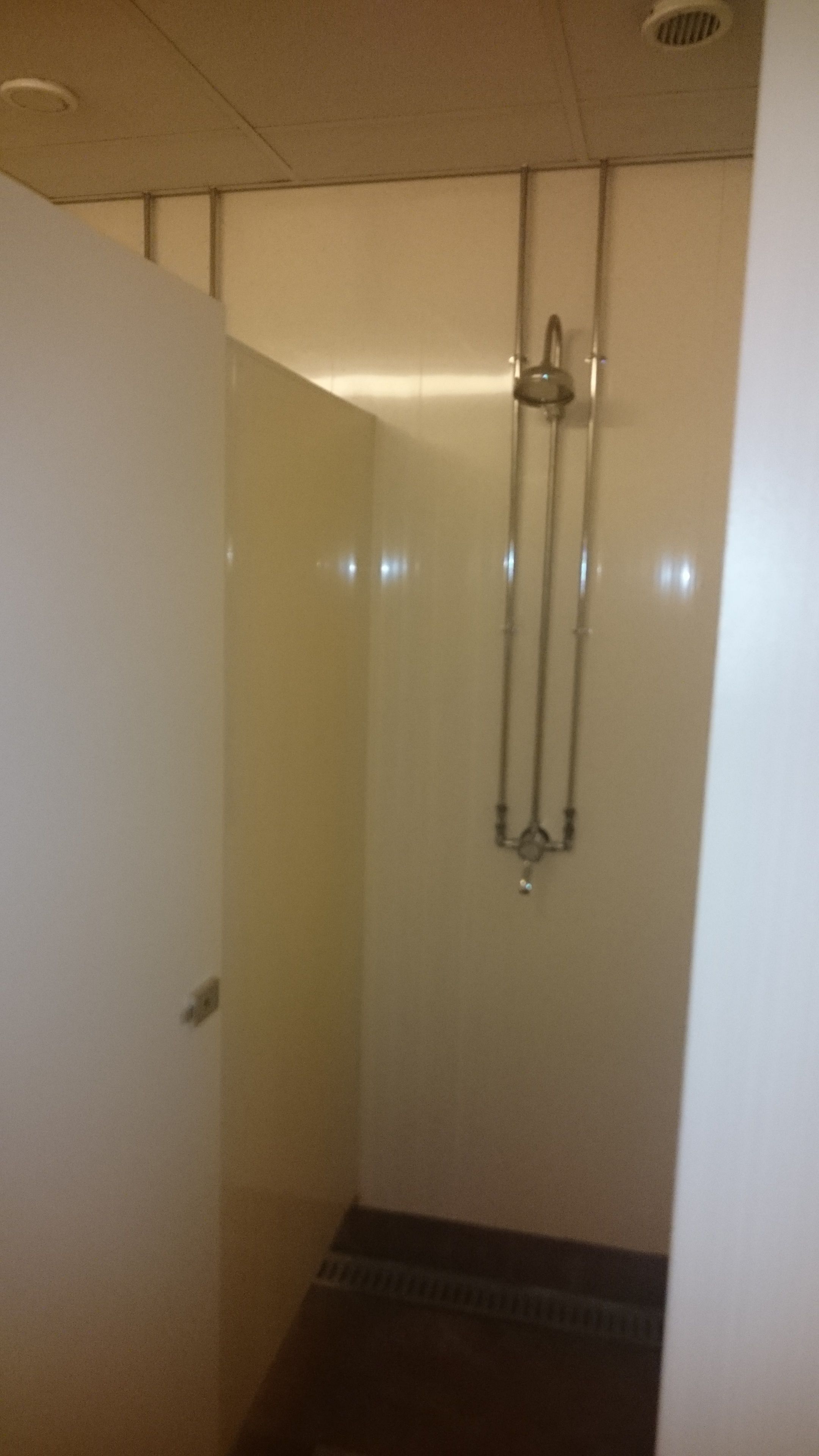 Een kleine, afgesloten douchecabine met een glazen deur en een douchekop aan de muur.