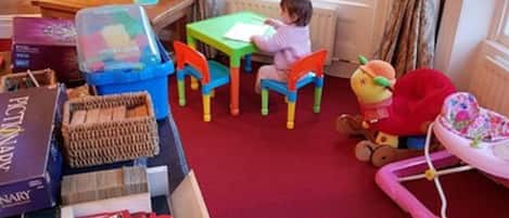 A child's playroom with a window, toys, and educational materials.