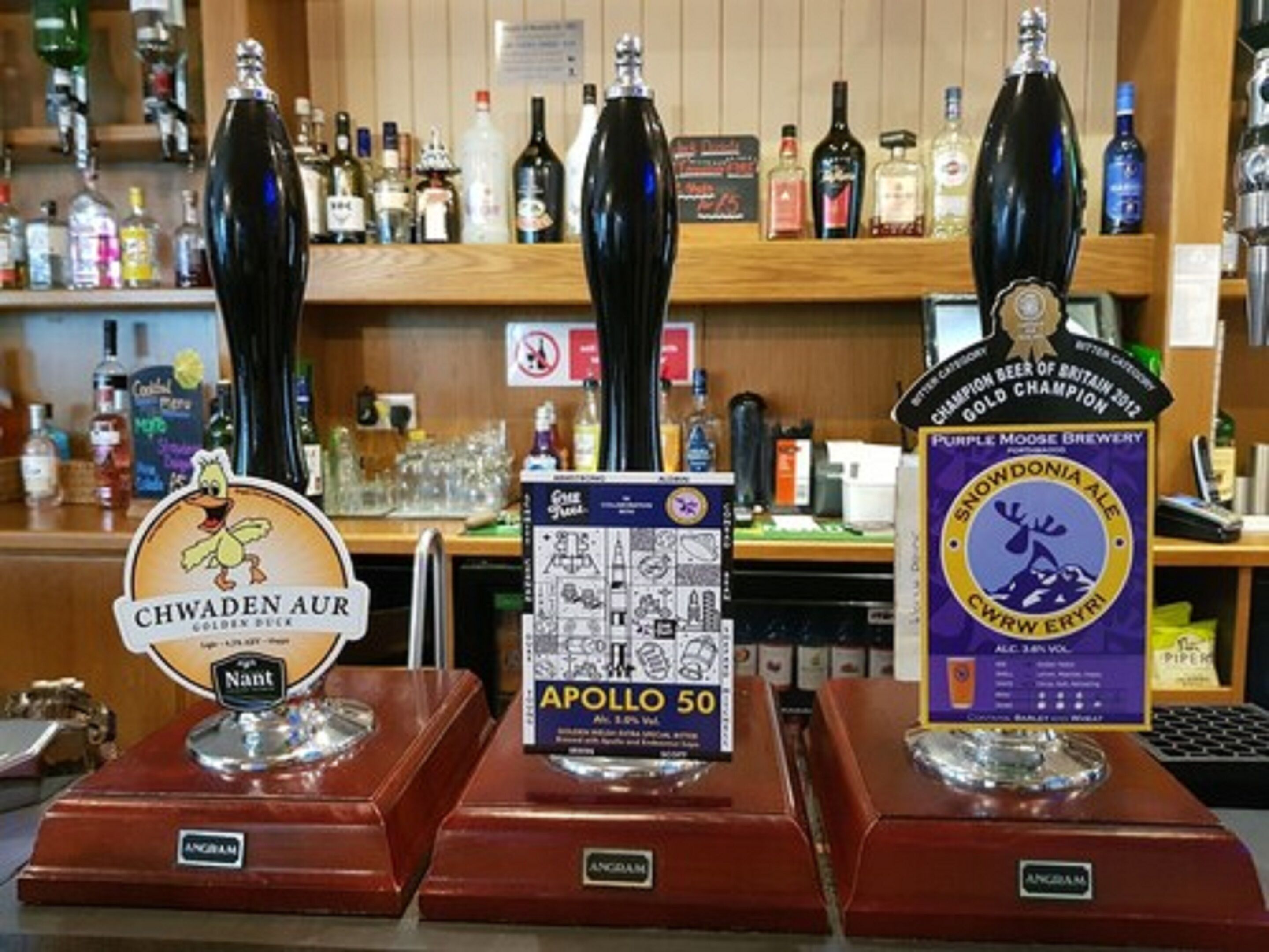 Tres grifos de cerveza con etiquetas: 'Chwaden Aur', 'Apollo 50' y 'Snowdonia Ale'.