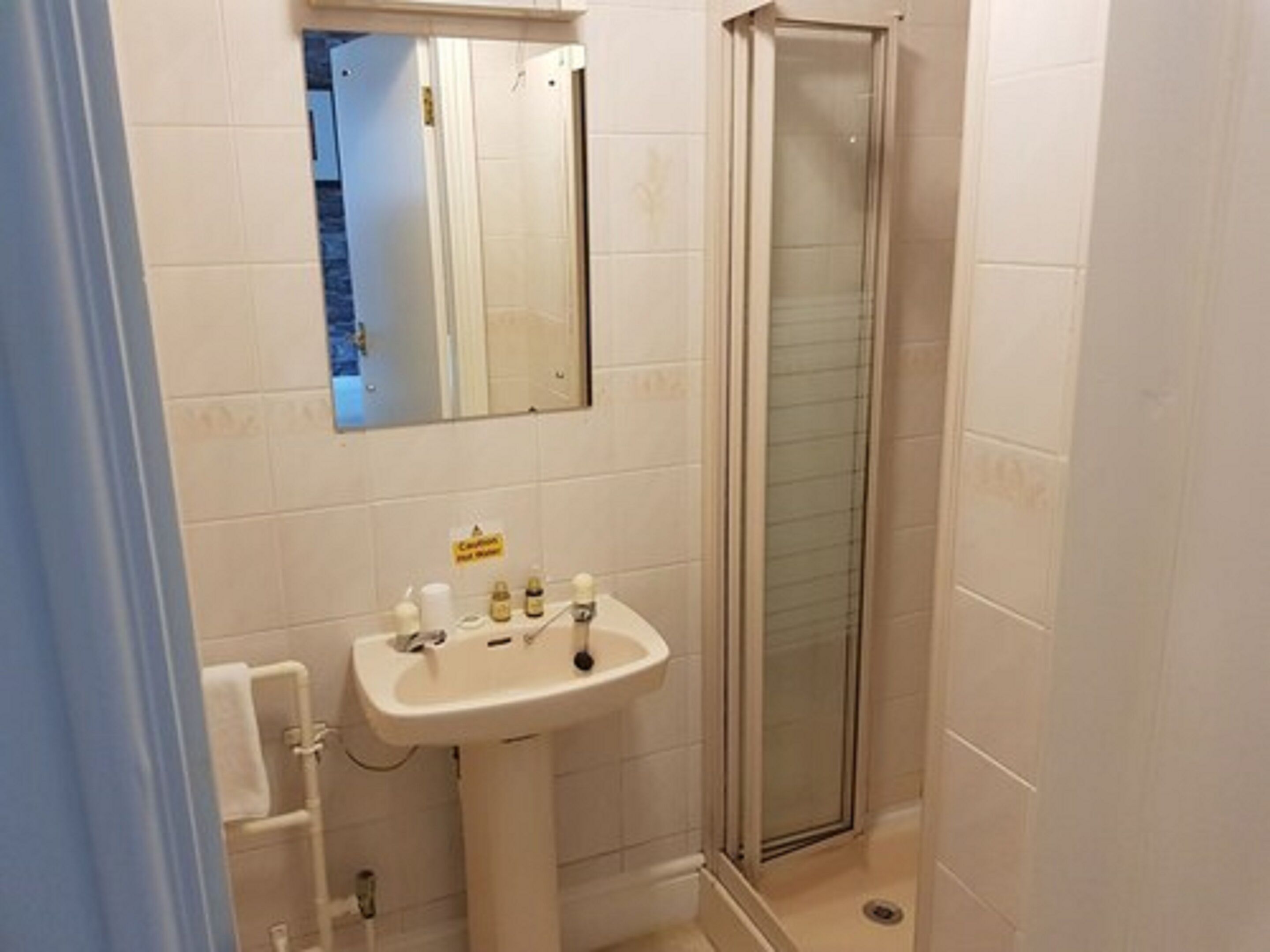 A bathroom with a sink, mirror, and shower.