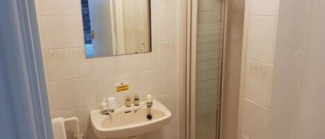 A bathroom with a sink, mirror, and shower.