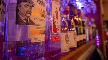 Una hilera de botellas de licor con etiquetas, incluyendo 'Sadler's Peaky Blinder Spiced Dry Gin' y 'Beefeater Pink Strawberry'.