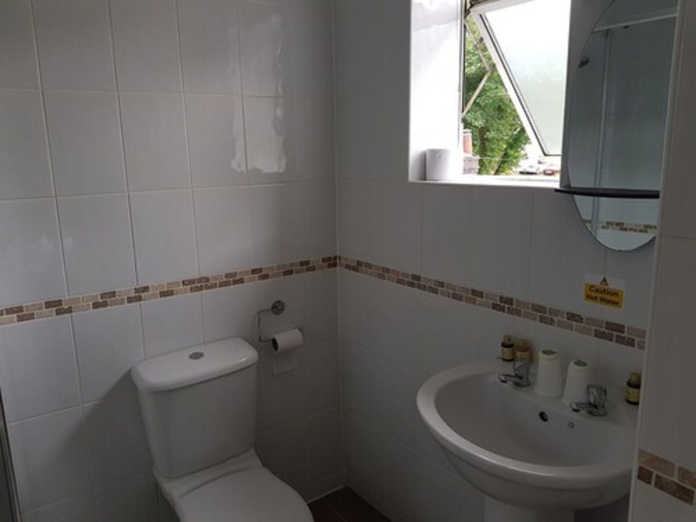 A small bathroom with a toilet, sink, and a window.