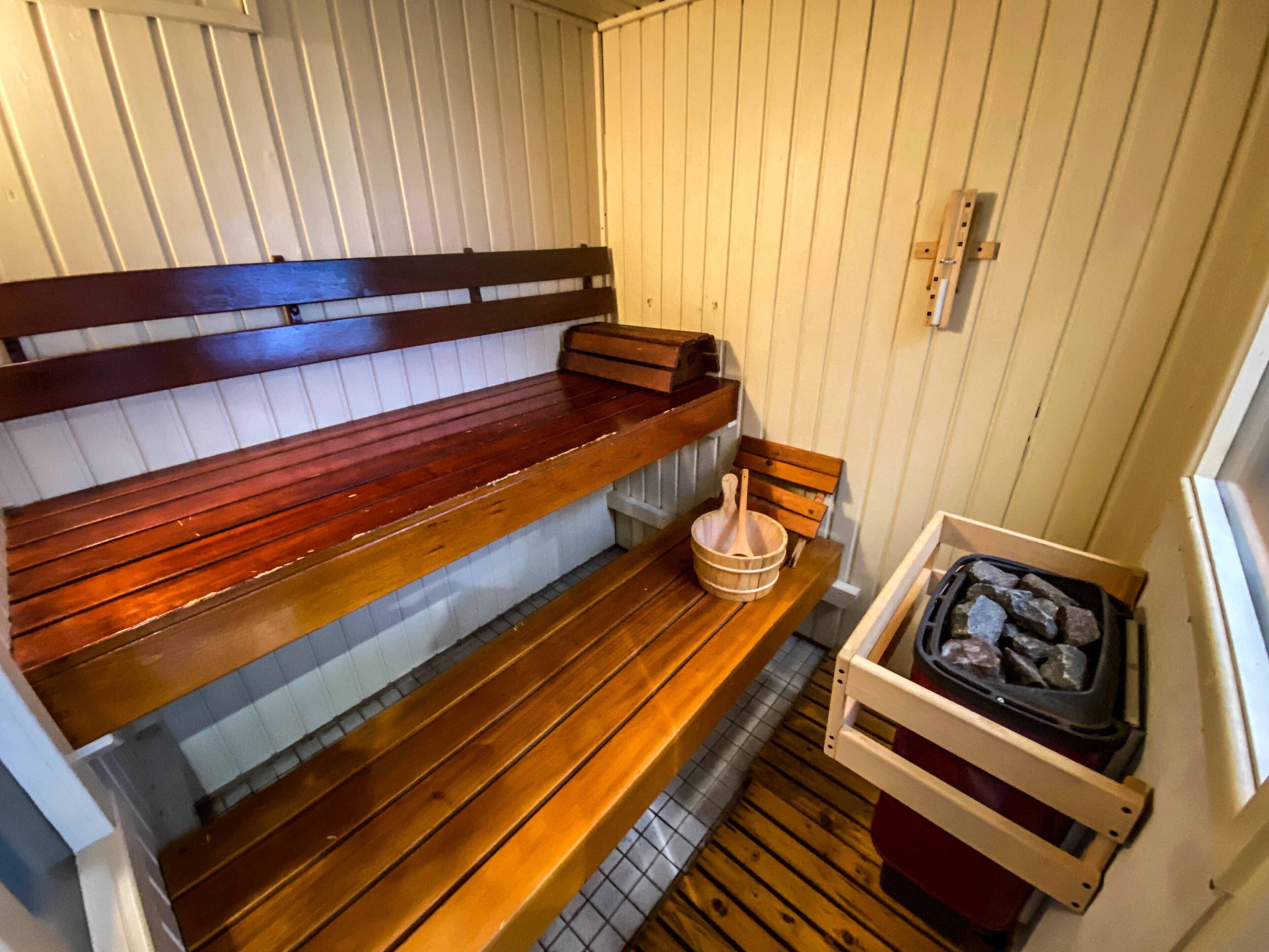 Eine Sauna mit Holzbänken und einem Steingefäß.