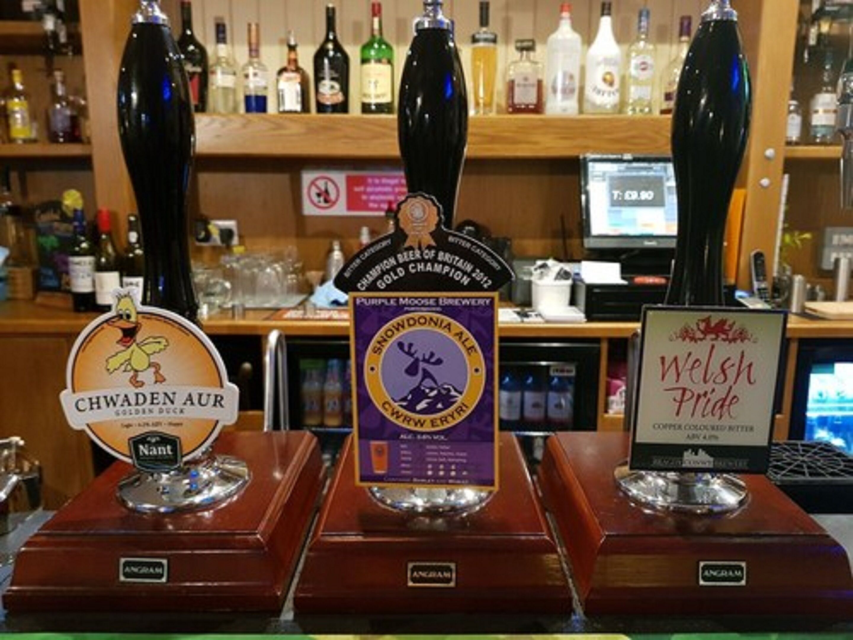 Een bar met drie biertaps, gelabeld 'Chwaden Aur', 'Purple Moose Brewery' en 'Welsh Pride'.