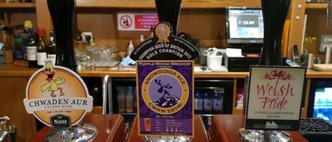 Een bar met drie biertaps, gelabeld 'Chwaden Aur', 'Purple Moose Brewery' en 'Welsh Pride'.