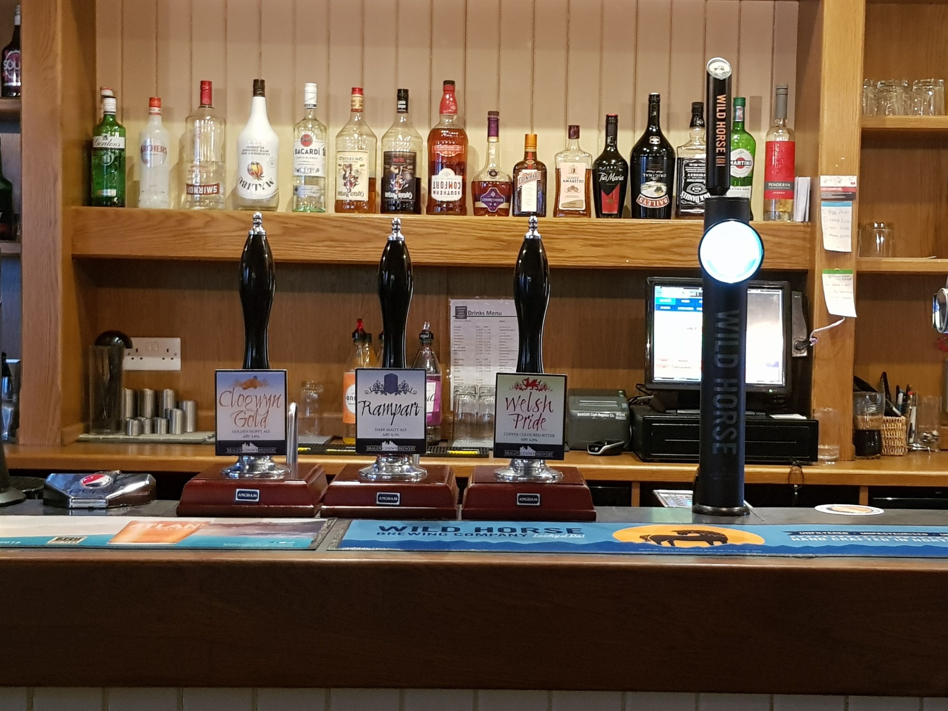 Eine Bar mit mehreren Spirituosenflaschen und Zapfhähnen, beschriftet mit verschiedenen Marken.